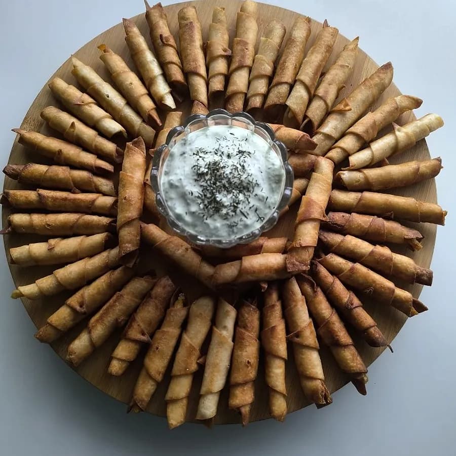 Zalogaji u obliku cigare sa dip sosom na drvenoj dasci